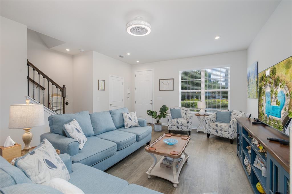 A living room features light blue sofas, a wooden coffee table, and a television console — 14496 PROMENADE PARKWAY, ODESSA, FL