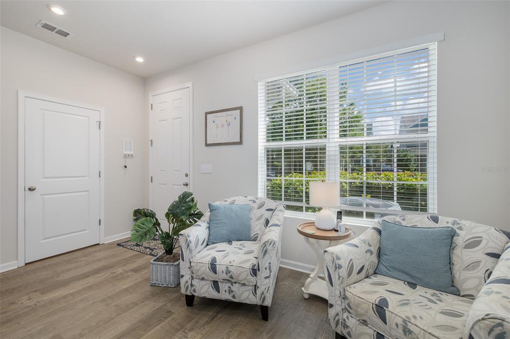 A bright room features two patterned armchairs, a side table, and a front entryway door — 14496 PROMENADE PARKWAY, ODESSA, FL