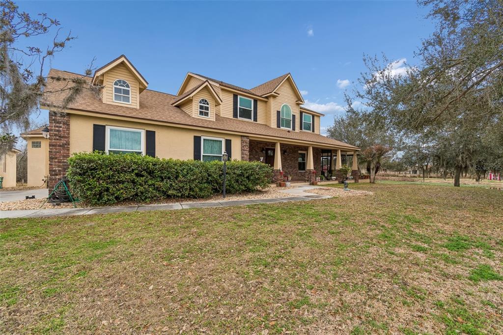 A two-story house with a tan exterior, brick accents, and a covered front porch — 2921 LAMPP ROAD, PLANT CITY, FL