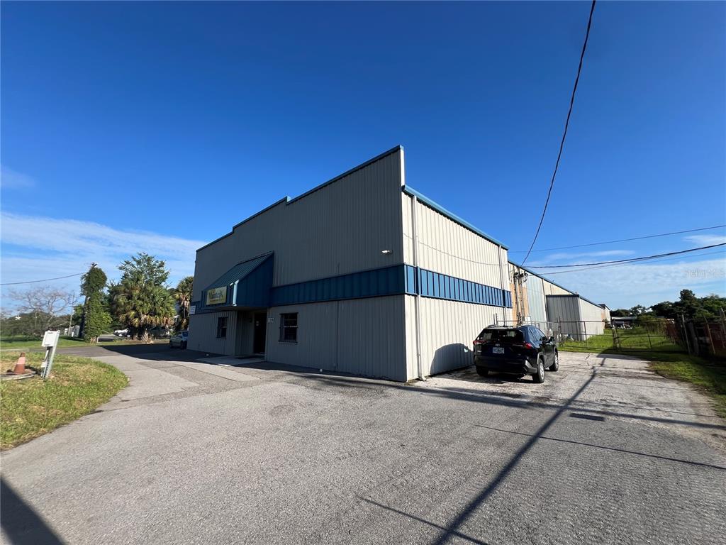 A gray metal industrial building with a blue awning stands on a paved lot — 5208 SAINT PAUL STREET, TAMPA, FL