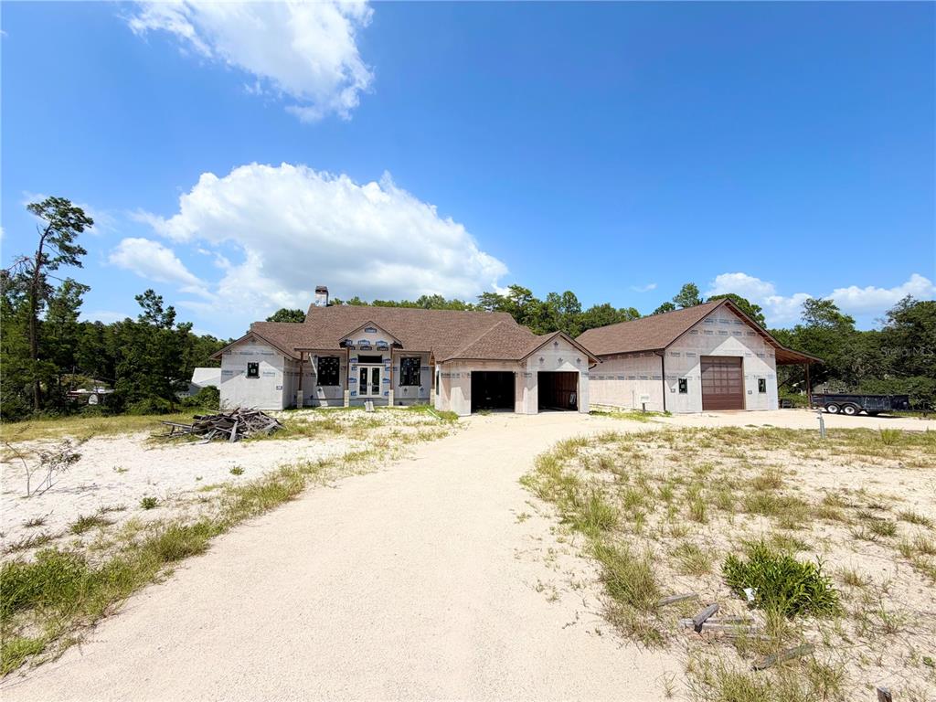 A newly constructed house with an attached garage and unfinished exterior siding under a blue sky — 7640 MOKENA COURT, NEW PORT RICHEY, FL