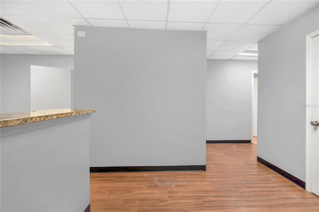 An office interior features gray walls, wood-look flooring, a drop ceiling, and a granite counter — 949 LANE AVENUE S, JACKSONVILLE, FL