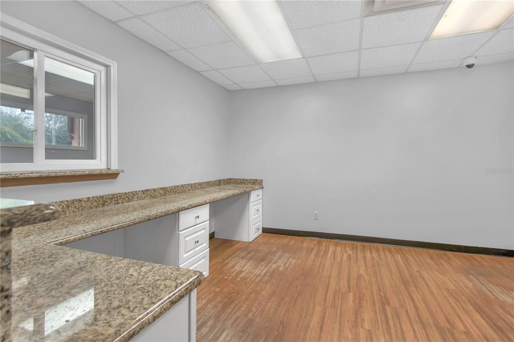 An office room features a long granite countertop, white cabinets, and wood-look flooring — 949 LANE AVENUE S, JACKSONVILLE, FL