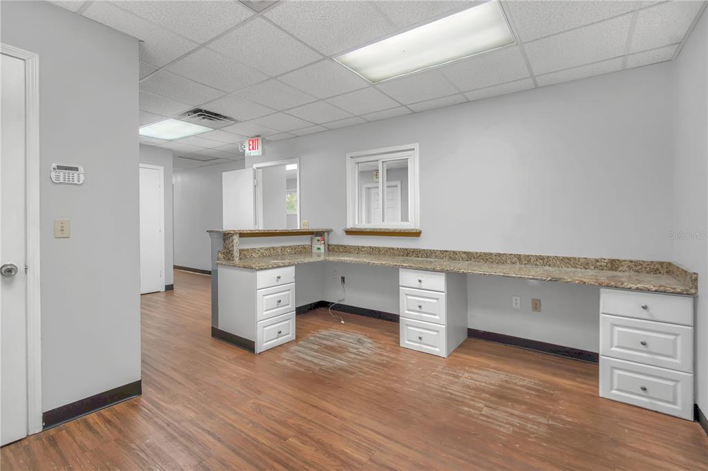 An office reception area features a granite-topped L-shaped desk, white cabinets, and wood-look flooring — 949 LANE AVENUE S, JACKSONVILLE, FL