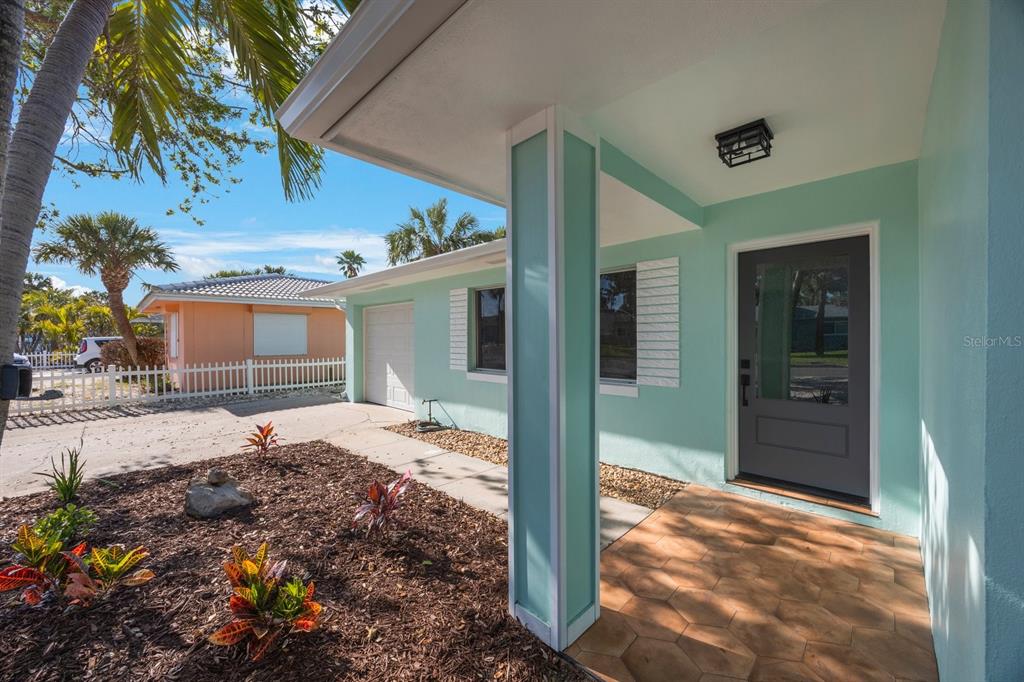 A light green house exterior features a covered entryway with hexagonal tiles and a pillar — 280 41ST AVENUE, ST PETE BEACH, FL