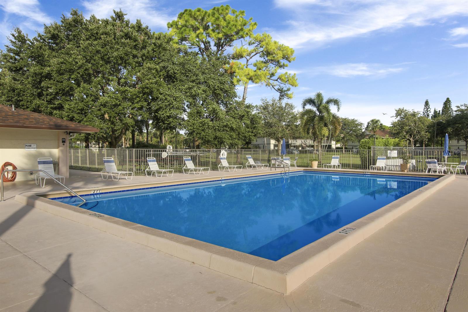 A rectangular outdoor swimming pool is surrounded by a concrete deck and lounge chairs — 6313 Chasewood Drive # B, Jupiter FL 33458, JUPITER, FL