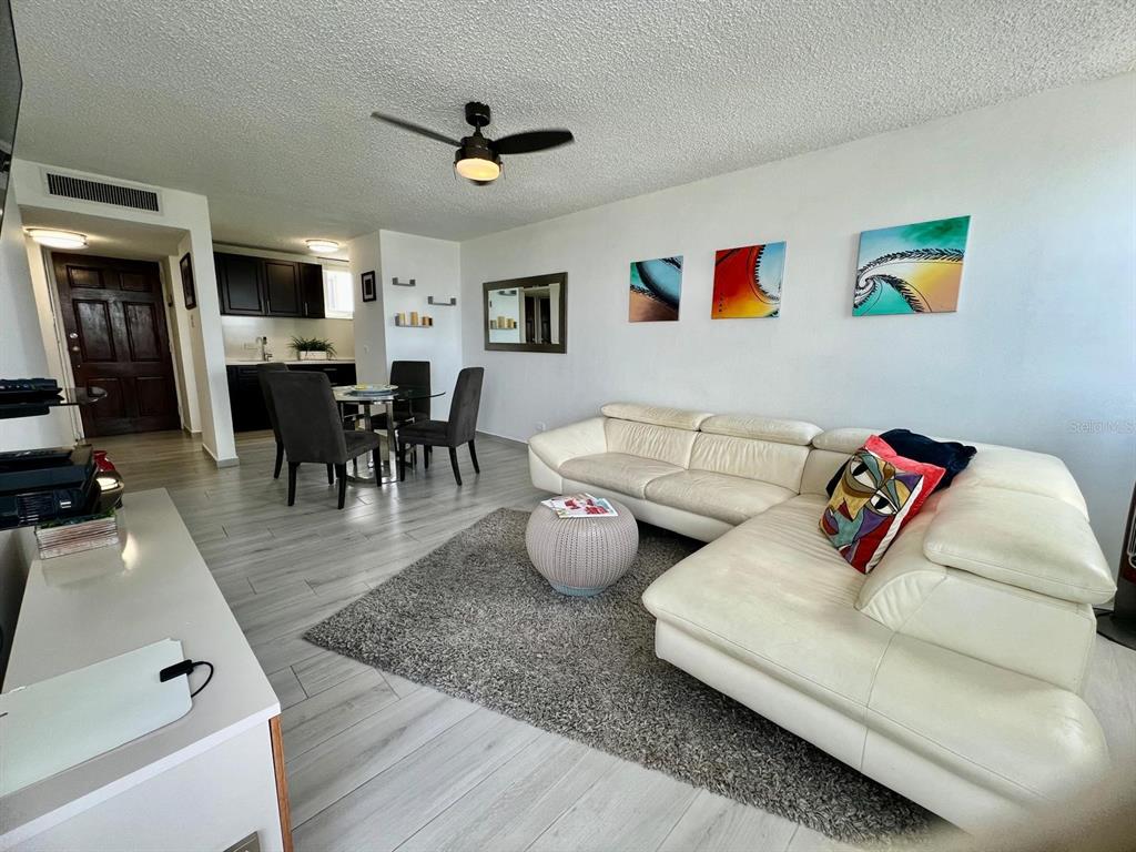 A living room features a white sectional sofa, a gray area rug, and a dining area — 5890 JOSÉ M. TARTAK AVENUE UNIT 1104 A, CAROLINA, PR