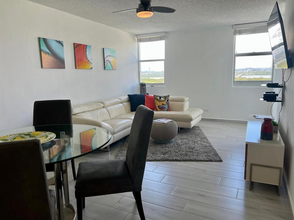 A living and dining area features a white sectional sofa, glass table, and large windows — 5890 JOSÉ M. TARTAK AVENUE UNIT 1104 A, CAROLINA, PR