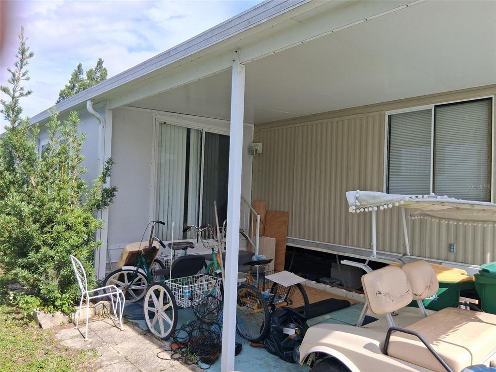 A covered patio area features a concrete floor, several bicycles, and a golf cart — 24437 HARBORVIEW ROAD UNIT 36, PUNTA GORDA, FL