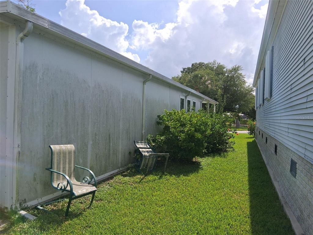 A side view of a house exterior shows a stained wall and a lawn — 24437 HARBORVIEW ROAD UNIT 36, PUNTA GORDA, FL