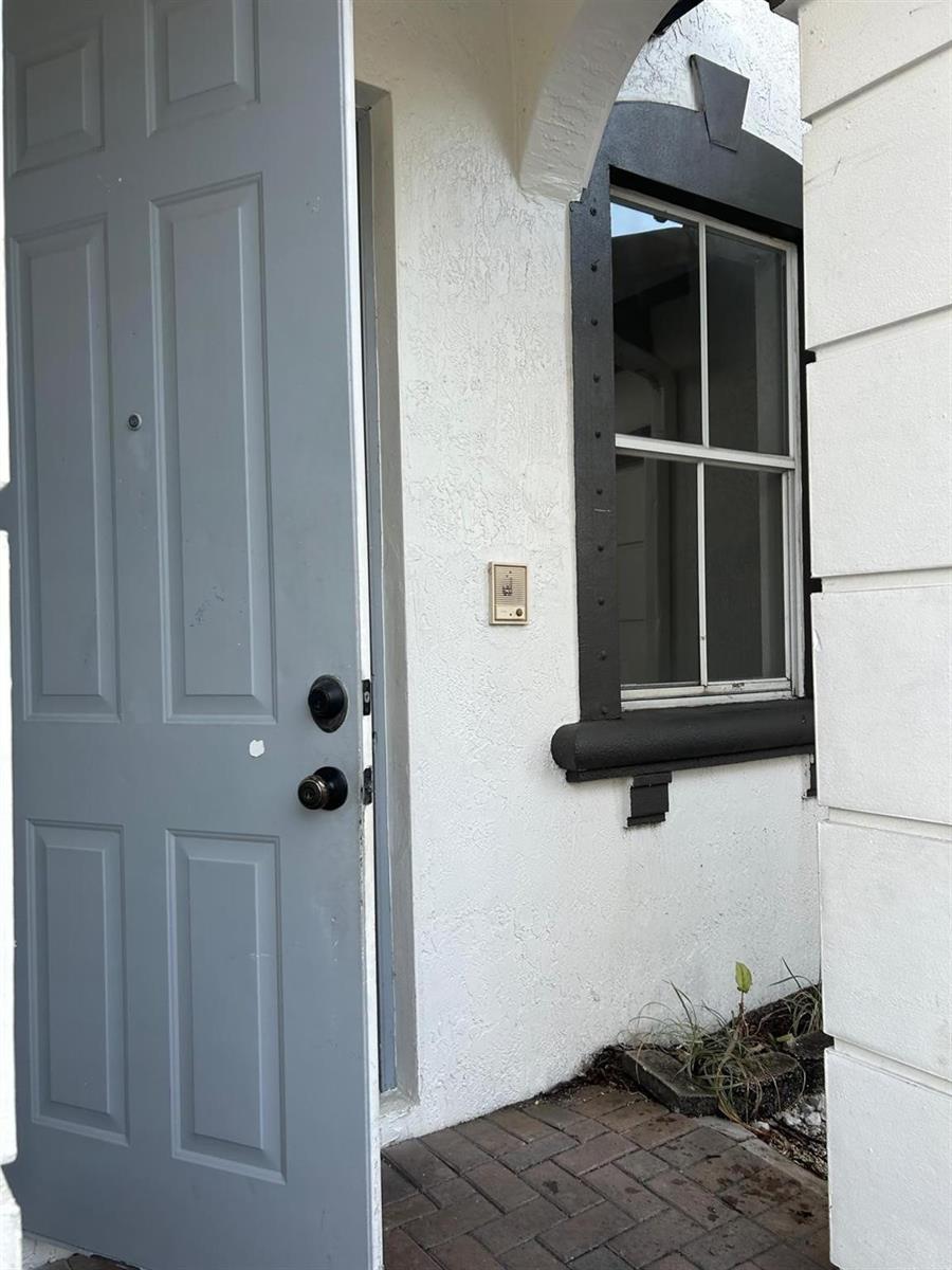An open gray door stands next to a window with a dark frame and trim — 11486 NW 77th Street, Doral FL 33178, DORAL, FL