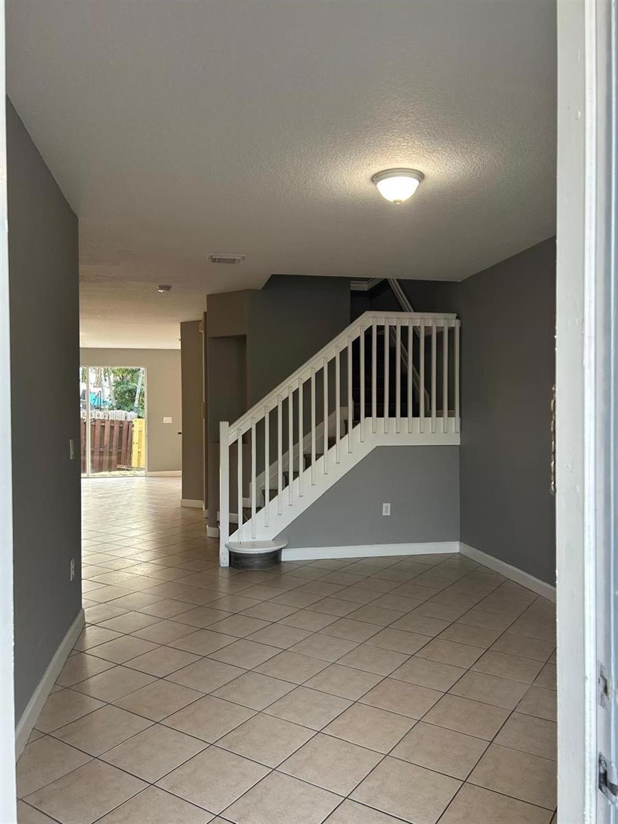 An entryway with tiled floors leads to a staircase with white railings and gray walls — 11486 NW 77th Street, Doral FL 33178, DORAL, FL