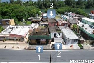 An aerial view shows a row of residential buildings along a road near water — PALO SECO PALO SECO, TOA BAJA, PR