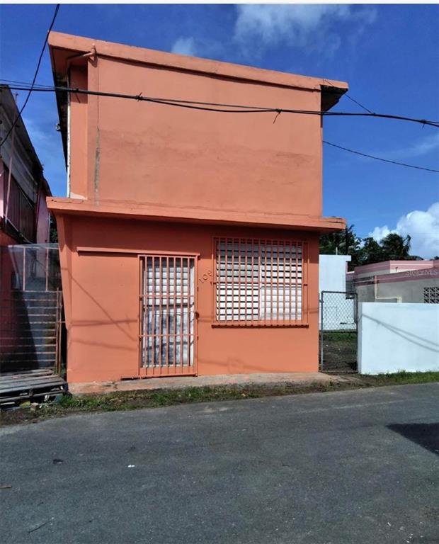 A two-story, peach-colored building features a metal-grated door and window on the ground floor — PALO SECO PALO SECO, TOA BAJA, PR