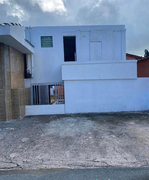 The exterior of a two-story white concrete building features a ground-level gated entrance and balcony — PALO SECO PALO SECO, TOA BAJA, PR