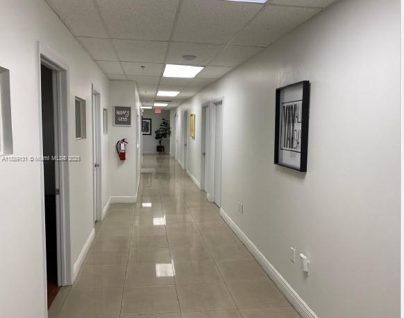 A long, brightly lit office hallway features white walls, tiled floors, and multiple closed doors — 3500 NW 114th Ave # 212, Doral FL 33178, DORAL, FL