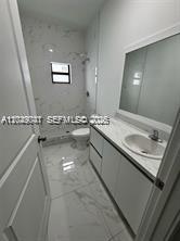 An empty room with white marble-patterned tile flooring and a black-framed window — 1717 NW 70th St, Miami FL 33147, MIAMI, FL