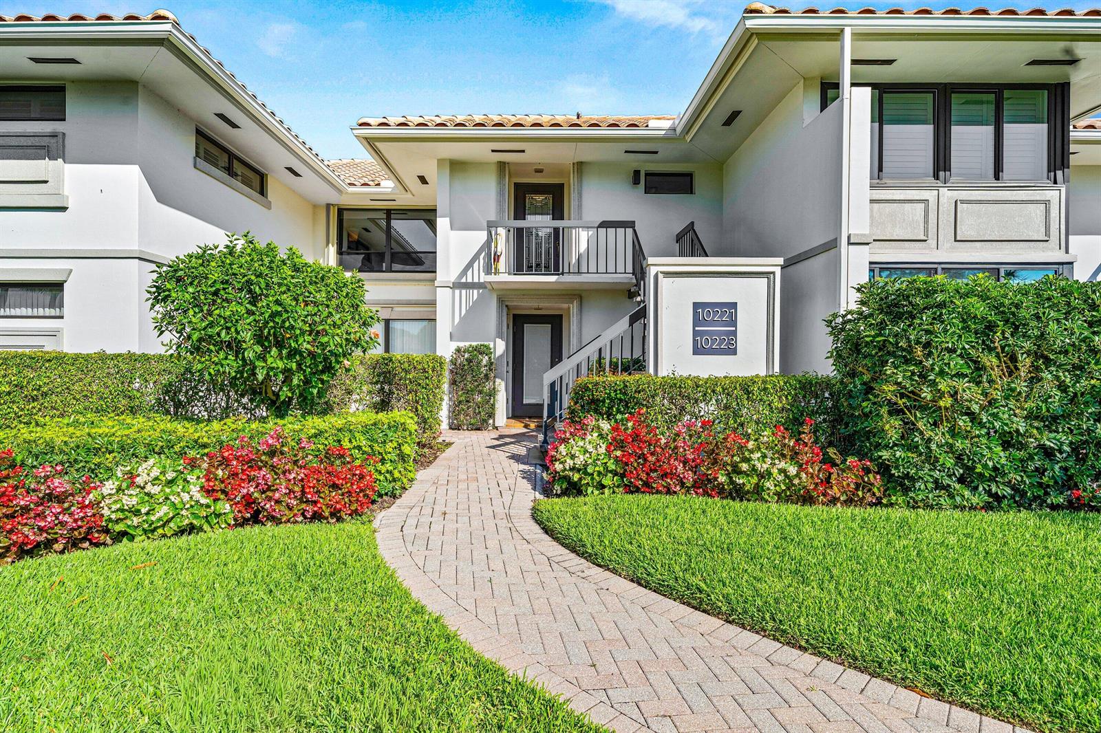 A brick walkway leads to the entrance of a two-story building with landscaped gardens — 10221 Quail Covey Road, Boynton Beach FL 33436, BOYNTON BEACH, FL
