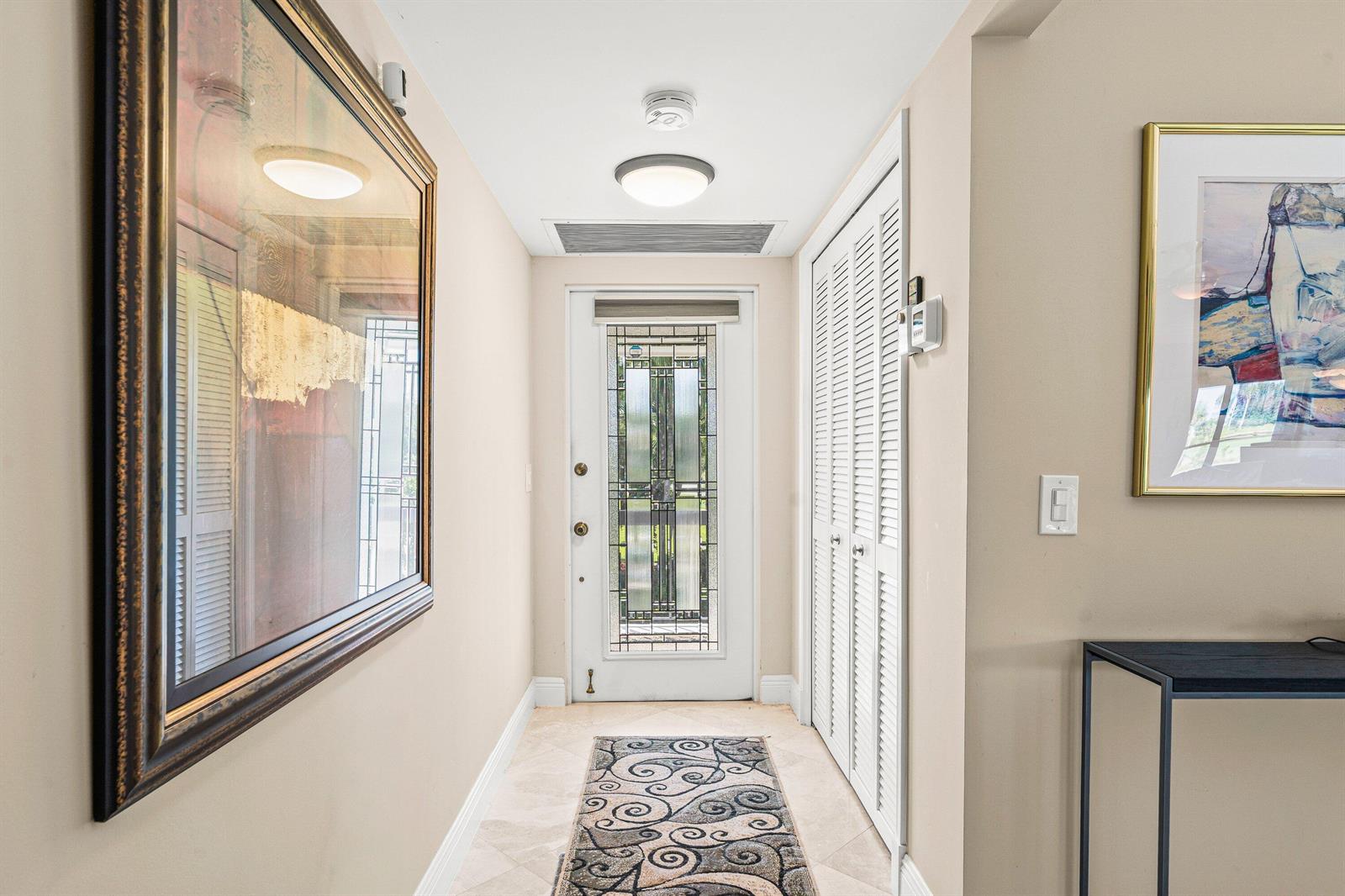 A hallway features a front door with decorative glass, tile flooring, and two framed artworks — 10221 Quail Covey Road, Boynton Beach FL 33436, BOYNTON BEACH, FL
