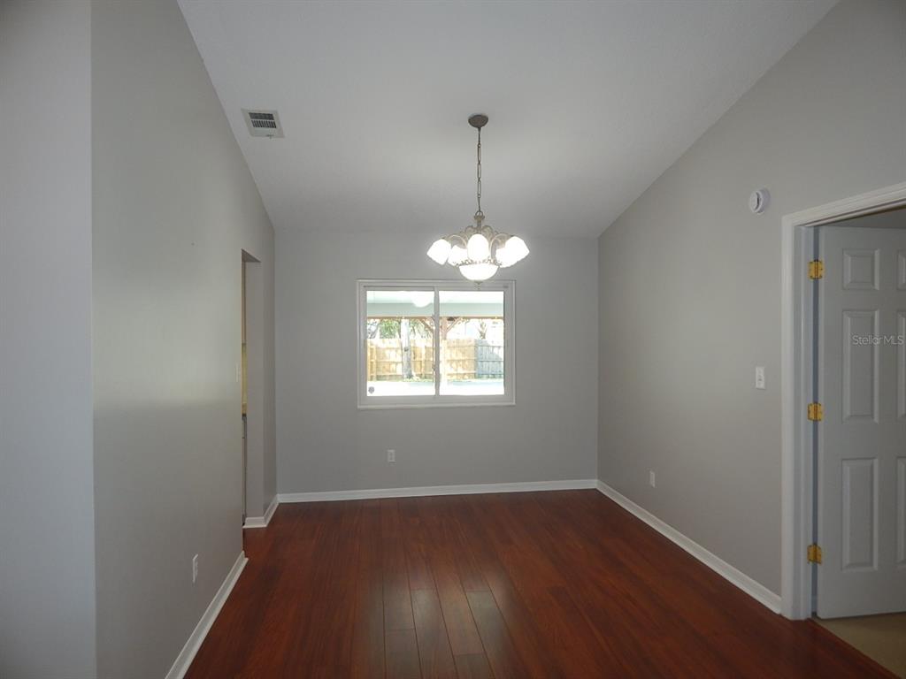 A dining room with gray walls, dark wood flooring, a chandelier, and a window — 4660 CREEKVIEW LANE, OVIEDO, FL