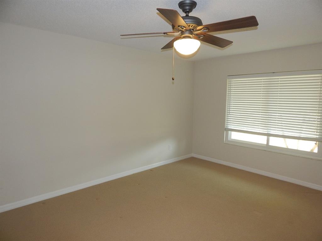An empty bedroom features beige carpet, light-colored walls, a ceiling fan, and a window — 4660 CREEKVIEW LANE, OVIEDO, FL