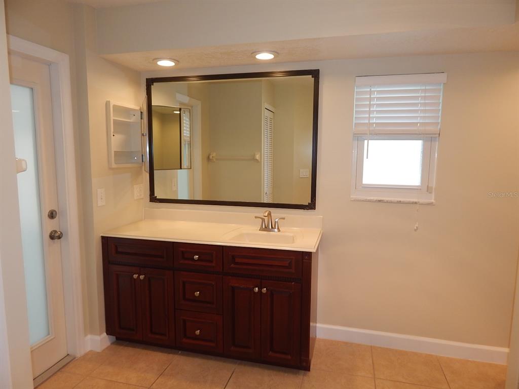 A bathroom features a dark wood vanity with a white countertop and a large mirror — 4660 CREEKVIEW LANE, OVIEDO, FL
