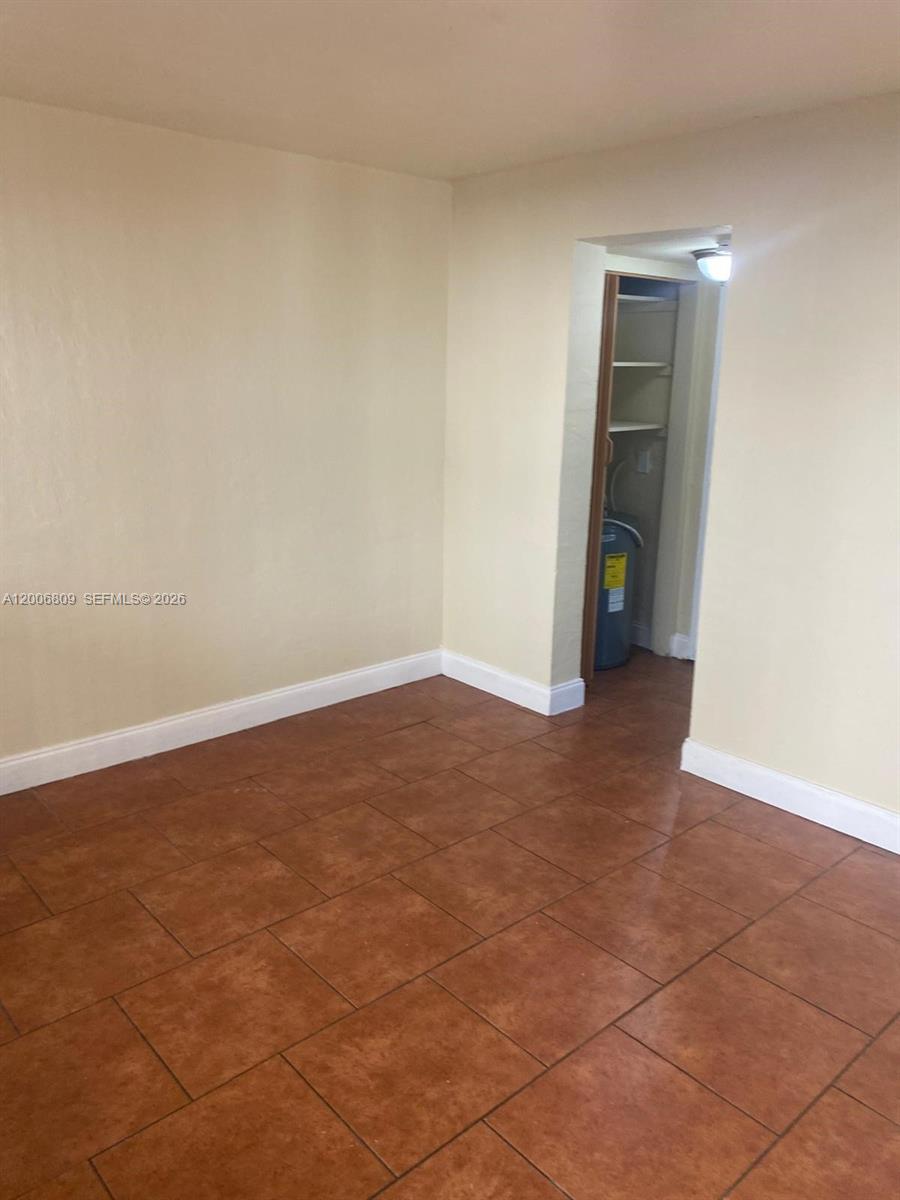 This room features light-colored walls and brown tile flooring with an open doorway to a utility area — 1319 NW 60th St # 4, Miami FL 33142, MIAMI, FL