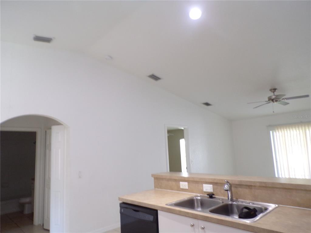 A kitchen sink and counter overlook a living area with a vaulted ceiling — 385 SUNFLOWER STREET UNIT A, PUNTA GORDA, FL
