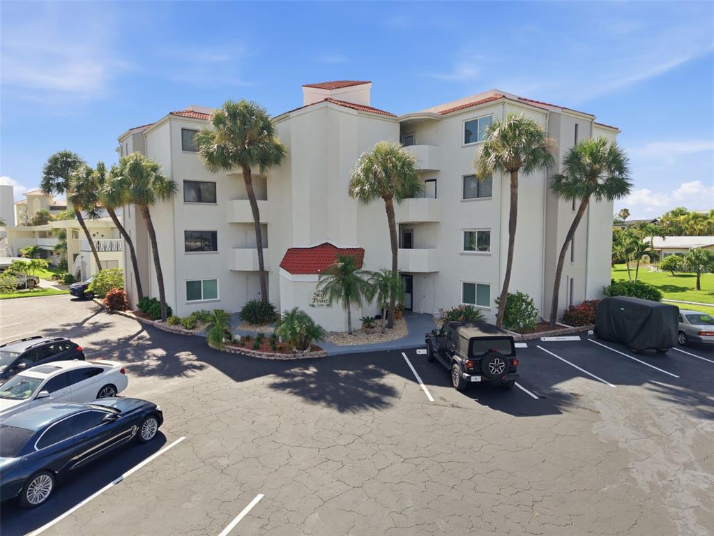 The exterior of a multi-story apartment building features a sign labeled Skiff Point 298 — 298 SKIFF POINT UNIT 103, CLEARWATER, FL