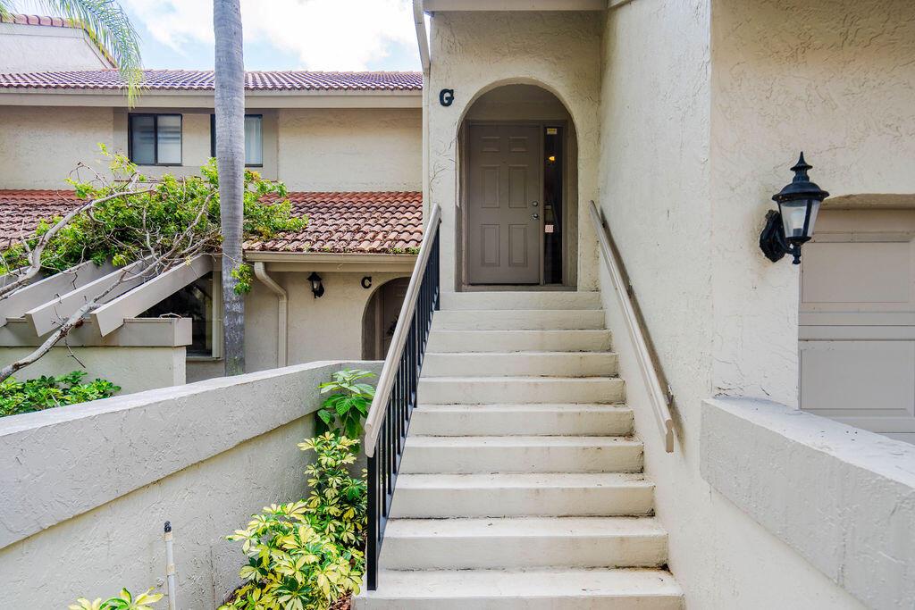 A set of concrete stairs leads up to a tan arched doorway labeled G — 5710 Coach House Circle # G, Boca Raton FL 33486, BOCA RATON, FL