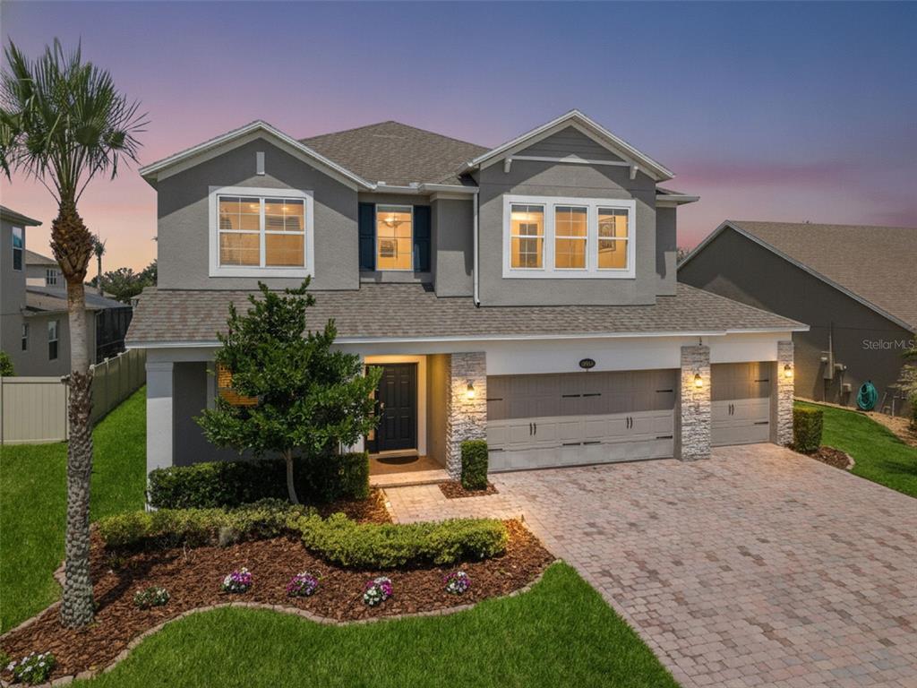 A two-story house with a gray stucco exterior, stone accents, and a paved driveway — 16044 CITRUS KNOLL DRIVE, WINTER GARDEN, FL