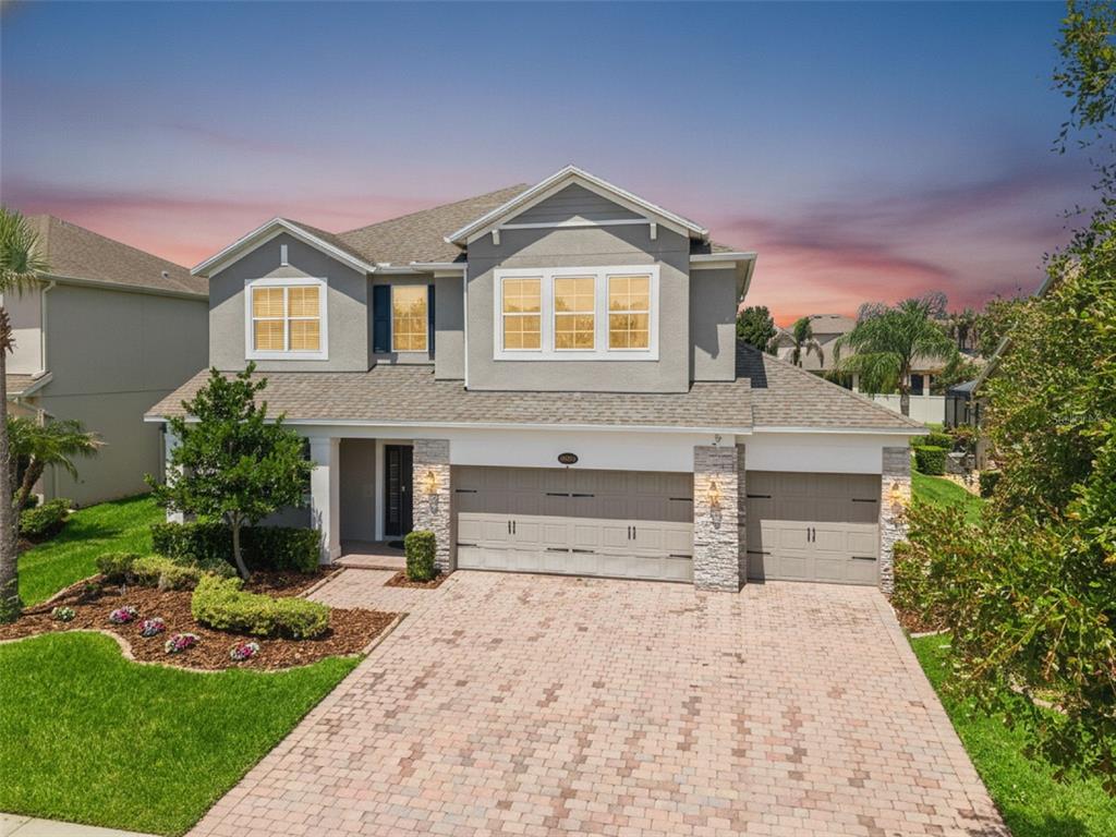 A two-story suburban house with a gray stucco exterior, stone accents, and a paved driveway — 16044 CITRUS KNOLL DRIVE, WINTER GARDEN, FL