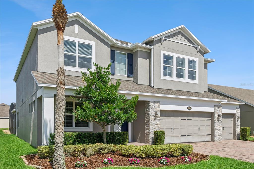 A two-story suburban house with a gray stucco exterior, stone accents, and a paved driveway — 16044 CITRUS KNOLL DRIVE, WINTER GARDEN, FL