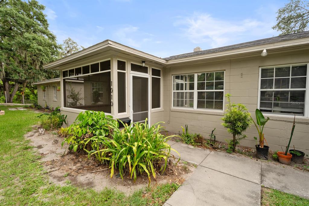 A beige concrete block house features a screened-in porch with the house number 1010 displayed — 1008 - 1014 E CENTRAL BOULEVARD, ORLANDO, FL