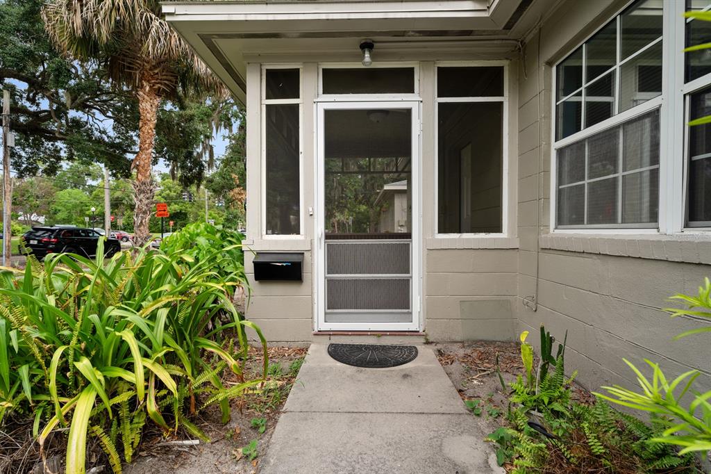 A concrete walkway leads to the screened front porch of a tan house — 1008 - 1014 E CENTRAL BOULEVARD, ORLANDO, FL