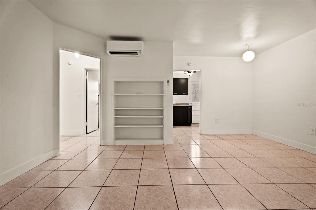 A room with light-colored tile flooring, built-in shelving, and a wall-mounted air conditioning unit — 1008 - 1014 E CENTRAL BOULEVARD, ORLANDO, FL