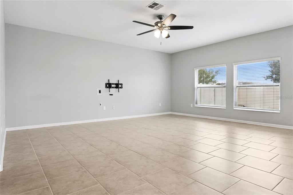 An empty room with light gray walls, tile flooring, a ceiling fan, and two windows — 781 TAURUS LANE, ST CLOUD, FL