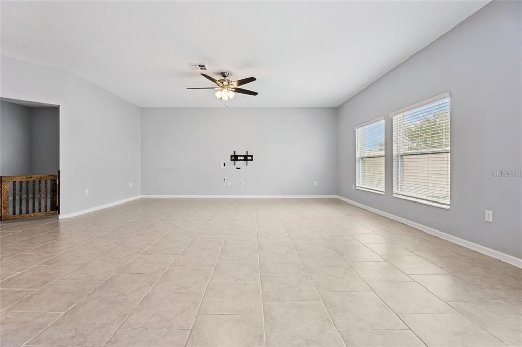 A spacious living room features light gray walls, large beige floor tiles, and a ceiling fan — 781 TAURUS LANE, ST CLOUD, FL