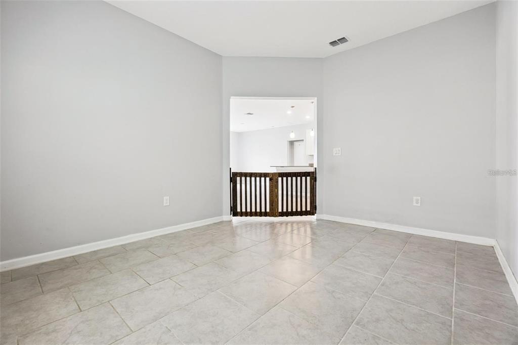 An empty room with light gray walls, tile flooring, and a wooden pet gate — 781 TAURUS LANE, ST CLOUD, FL