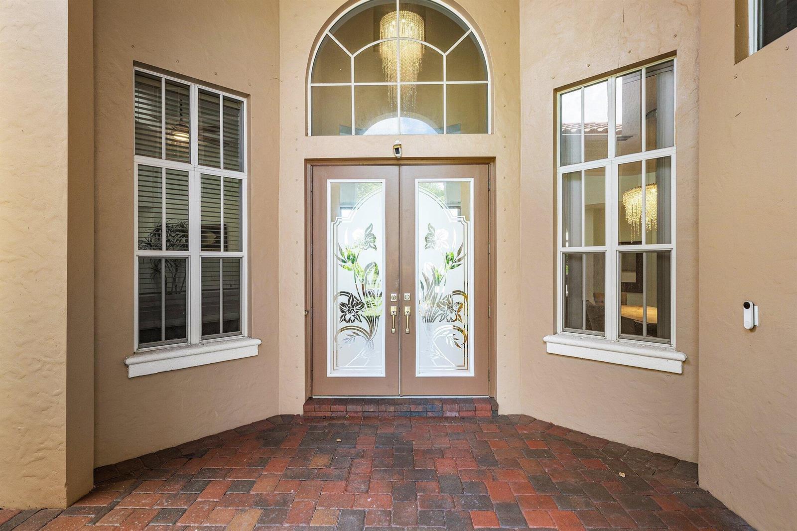 A front entryway features double glass doors with floral etching, side windows, and brick pavers — 3381 Lago De Talavera, Lake Worth FL 33467, LAKE WORTH, FL