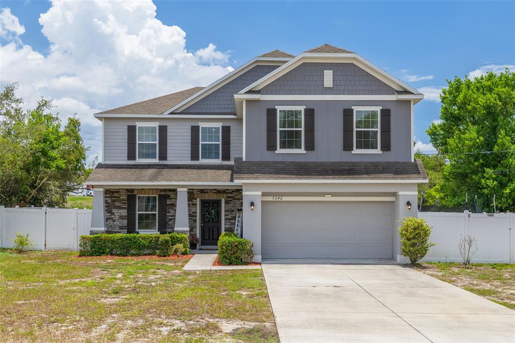 A two-story house with gray siding, a stone facade, and a two-car garage — 7242 LANDMARK DRIVE, SPRING HILL, FL