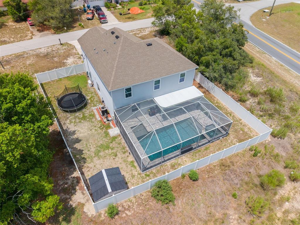 An aerial view shows a two-story house with a screened-in pool and a fenced backyard — 7242 LANDMARK DRIVE, SPRING HILL, FL