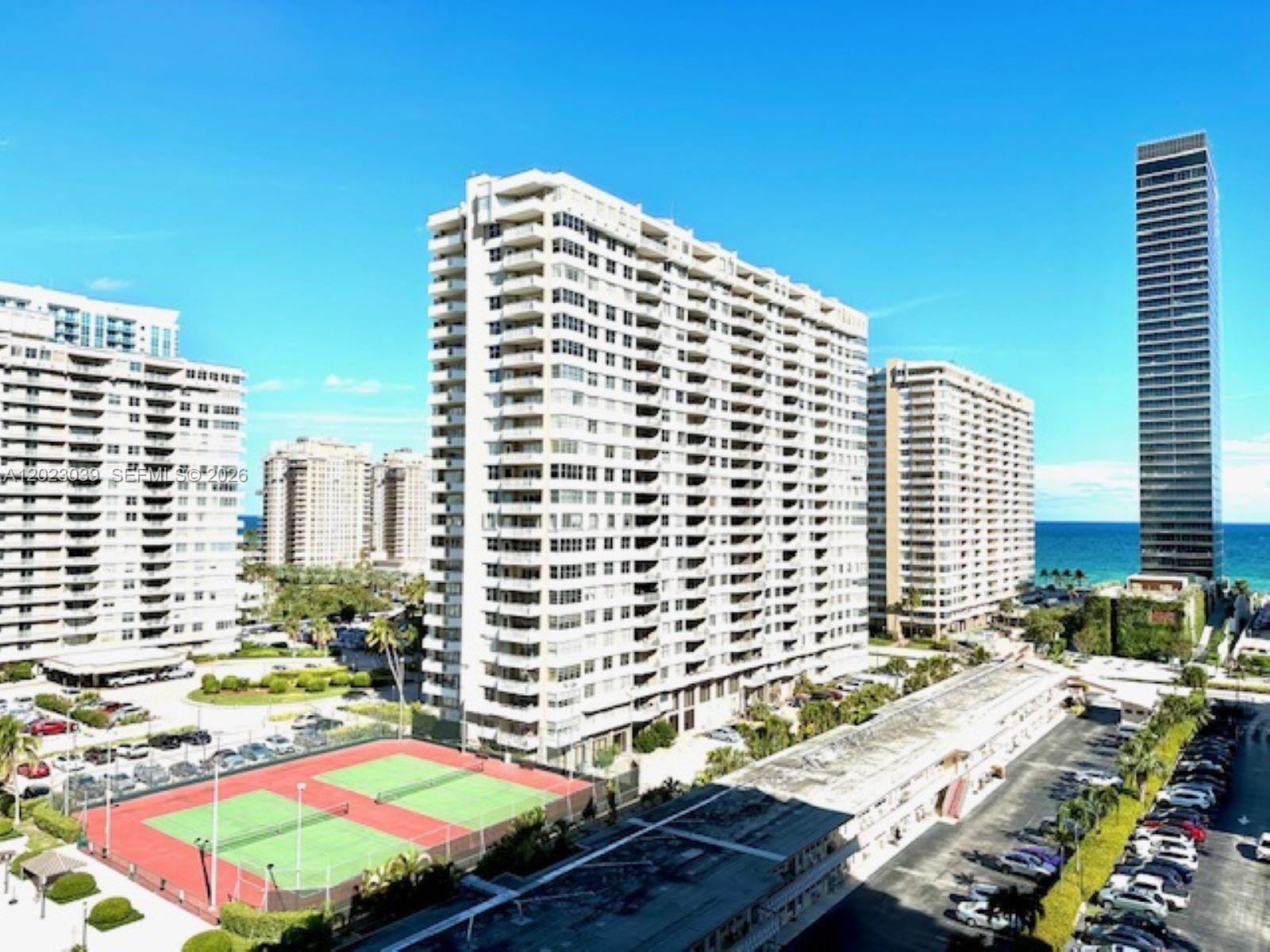 An aerial view shows several high-rise apartment buildings, a tennis court, and a parking lot — 2017 S Ocean Dr # 1107, Hallandale Beach FL 33009, HALLANDALE BEACH, FL