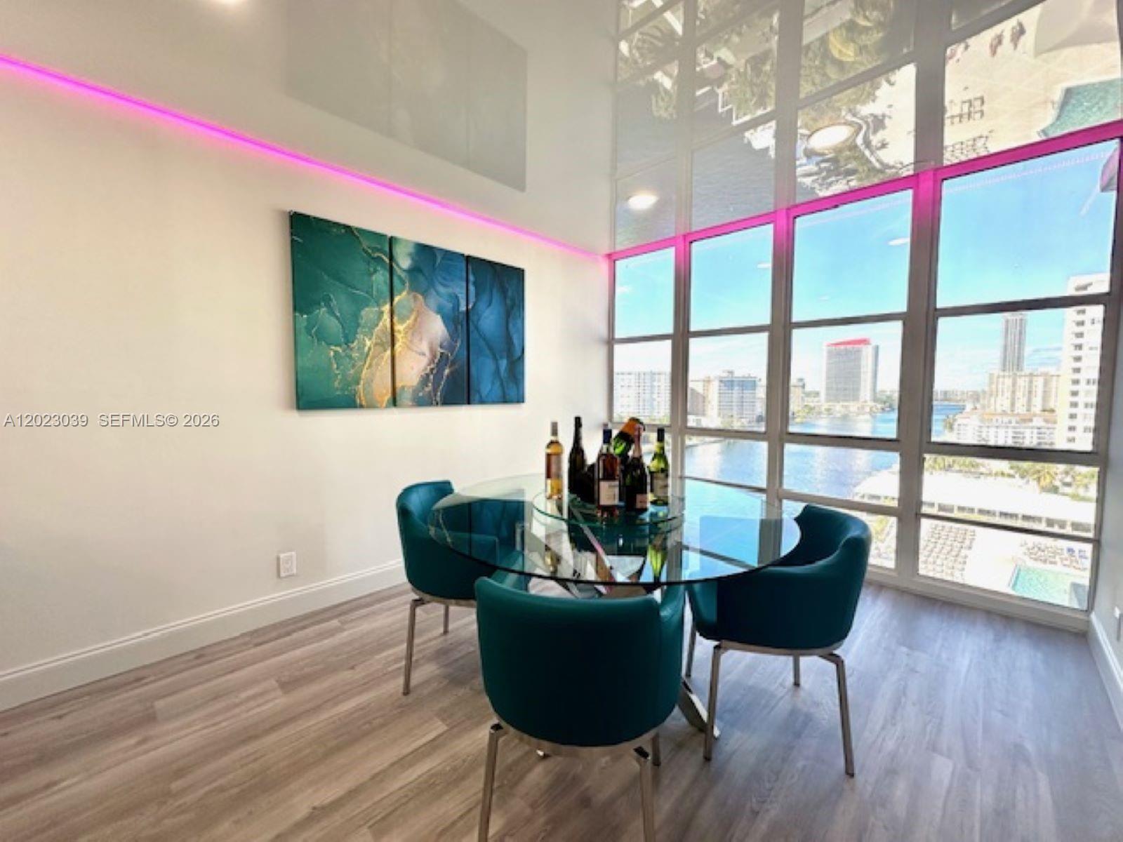 A dining room features a glass table, teal chairs, wall art, and floor-to-ceiling windows — 2017 S Ocean Dr # 1107, Hallandale Beach FL 33009, HALLANDALE BEACH, FL
