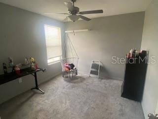 A bedroom features gray walls, carpeted flooring, a ceiling fan, and a hanging chair — 15510 WICKED STRONG STREET, SUN CITY CENTER, FL