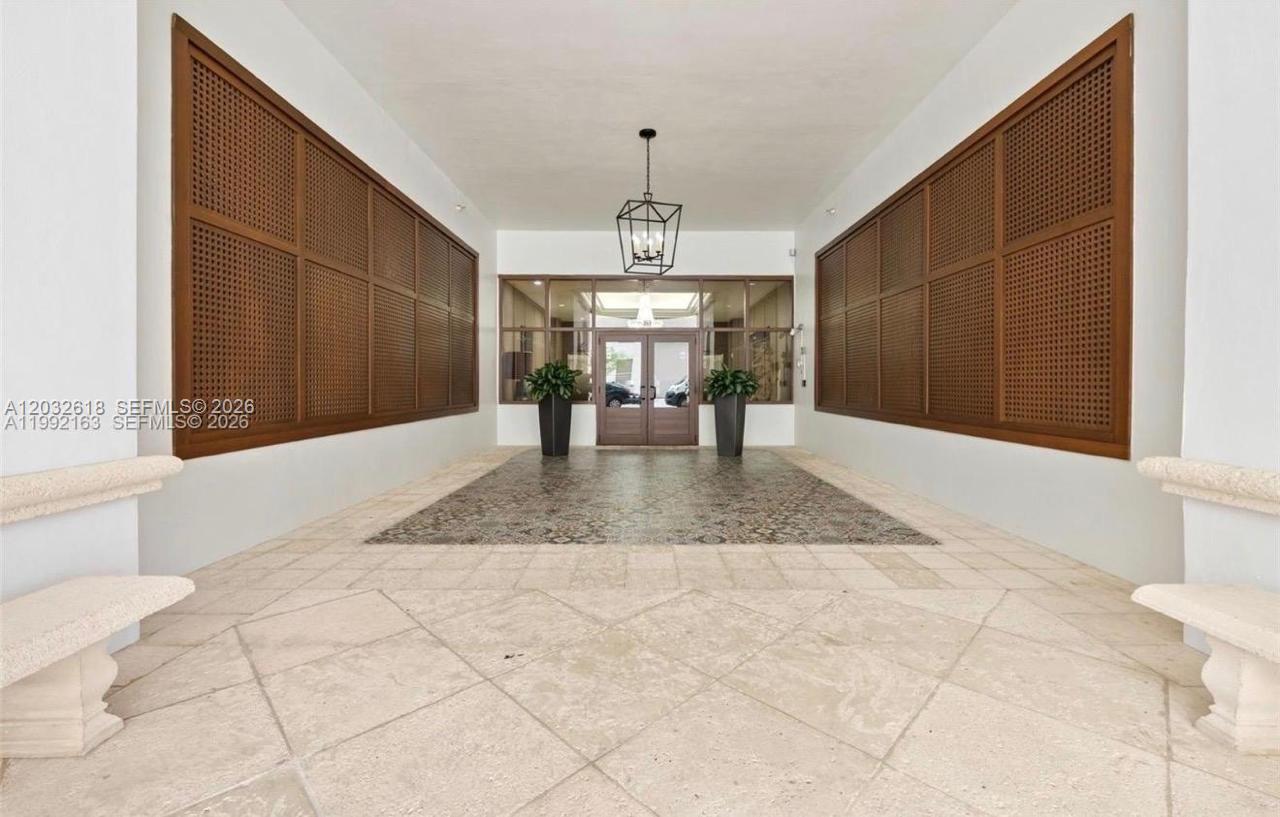 A symmetrical entryway features stone tile flooring, large wooden lattice panels, and a hanging lantern — 357 Almeria Ave # 802, Coral Gables FL 33134, CORAL GABLES, FL