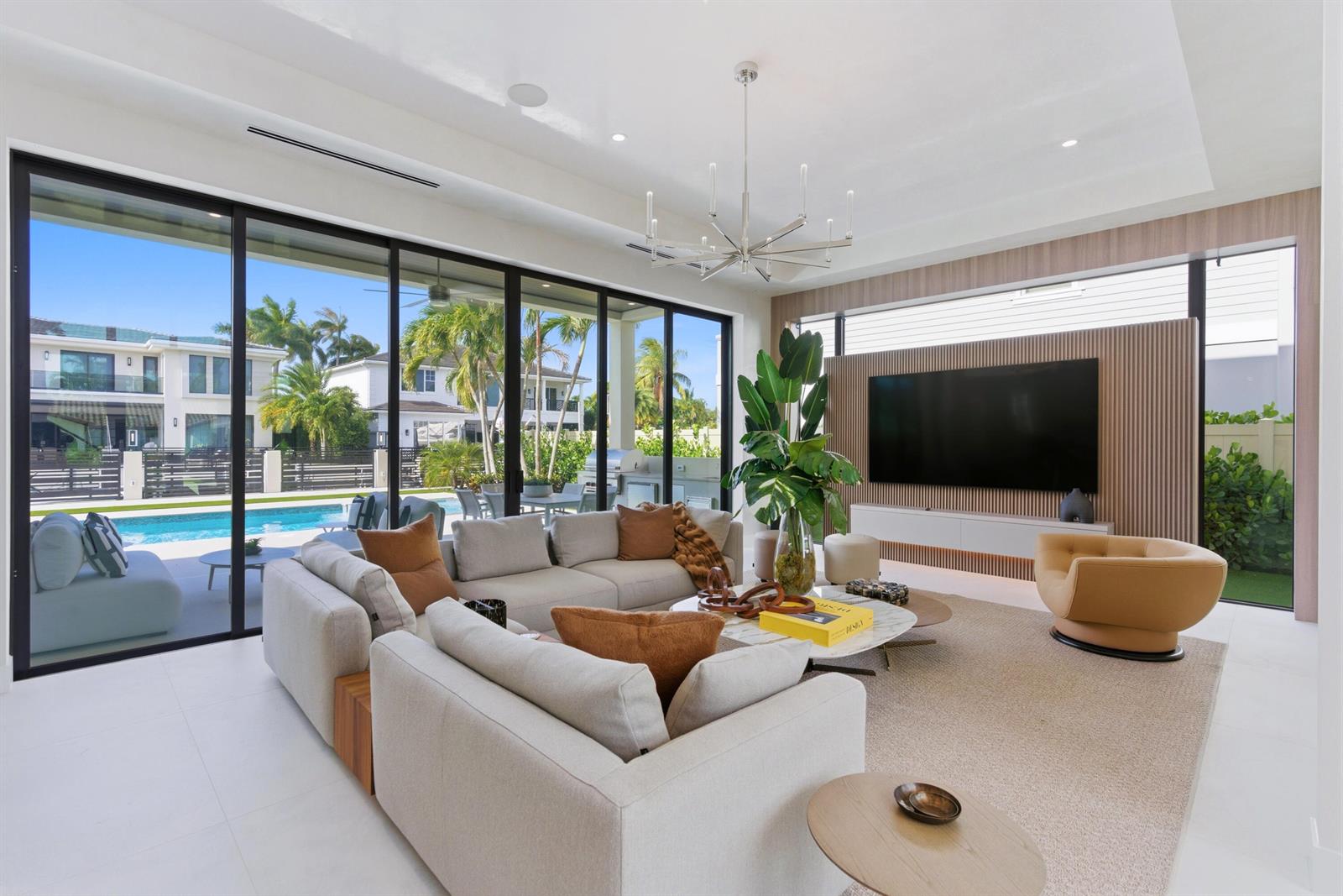 A modern living room features a large sectional sofa, wood-slat wall, and sliding glass doors — 511 Silver Lane, Boca Raton FL 33432, BOCA RATON, FL