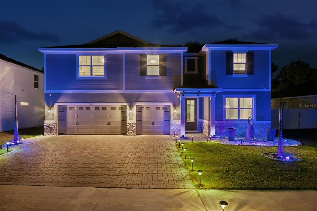 A two-story house with a two-car garage and illuminated landscaping at night — 887 ASTERFIELD LANE, DELAND, FL