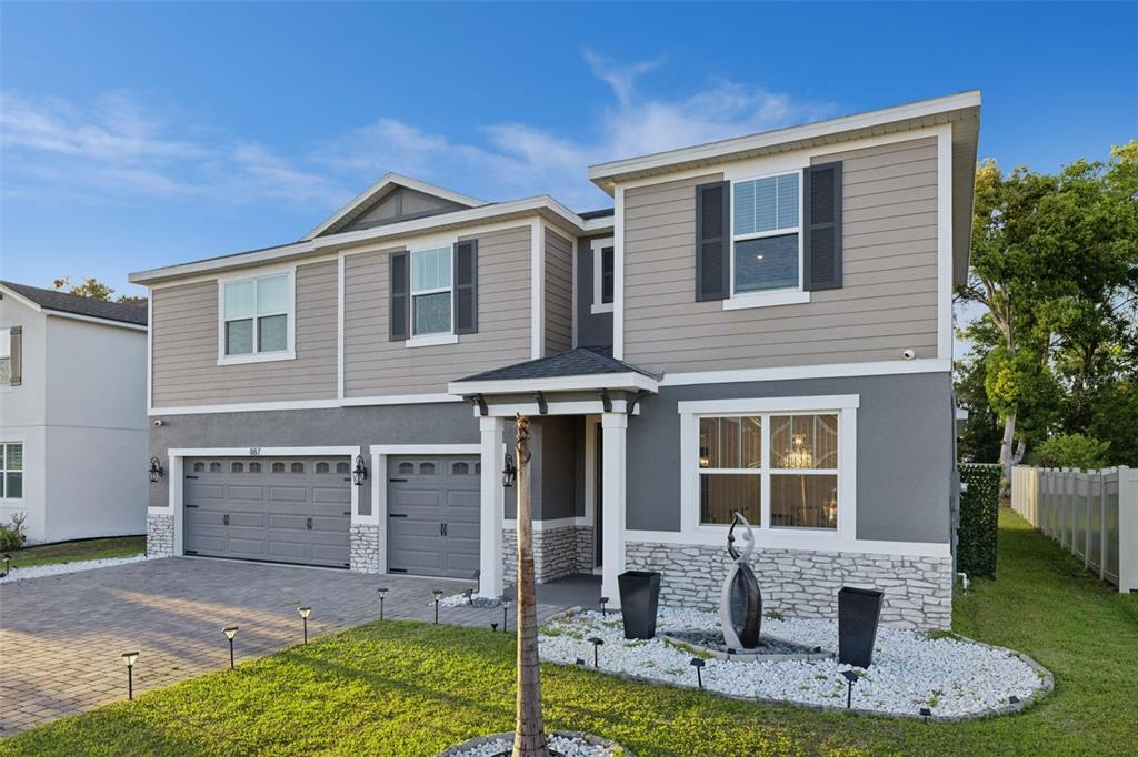A two-story house features a gray stucco and siding exterior with a stone veneer base — 887 ASTERFIELD LANE, DELAND, FL