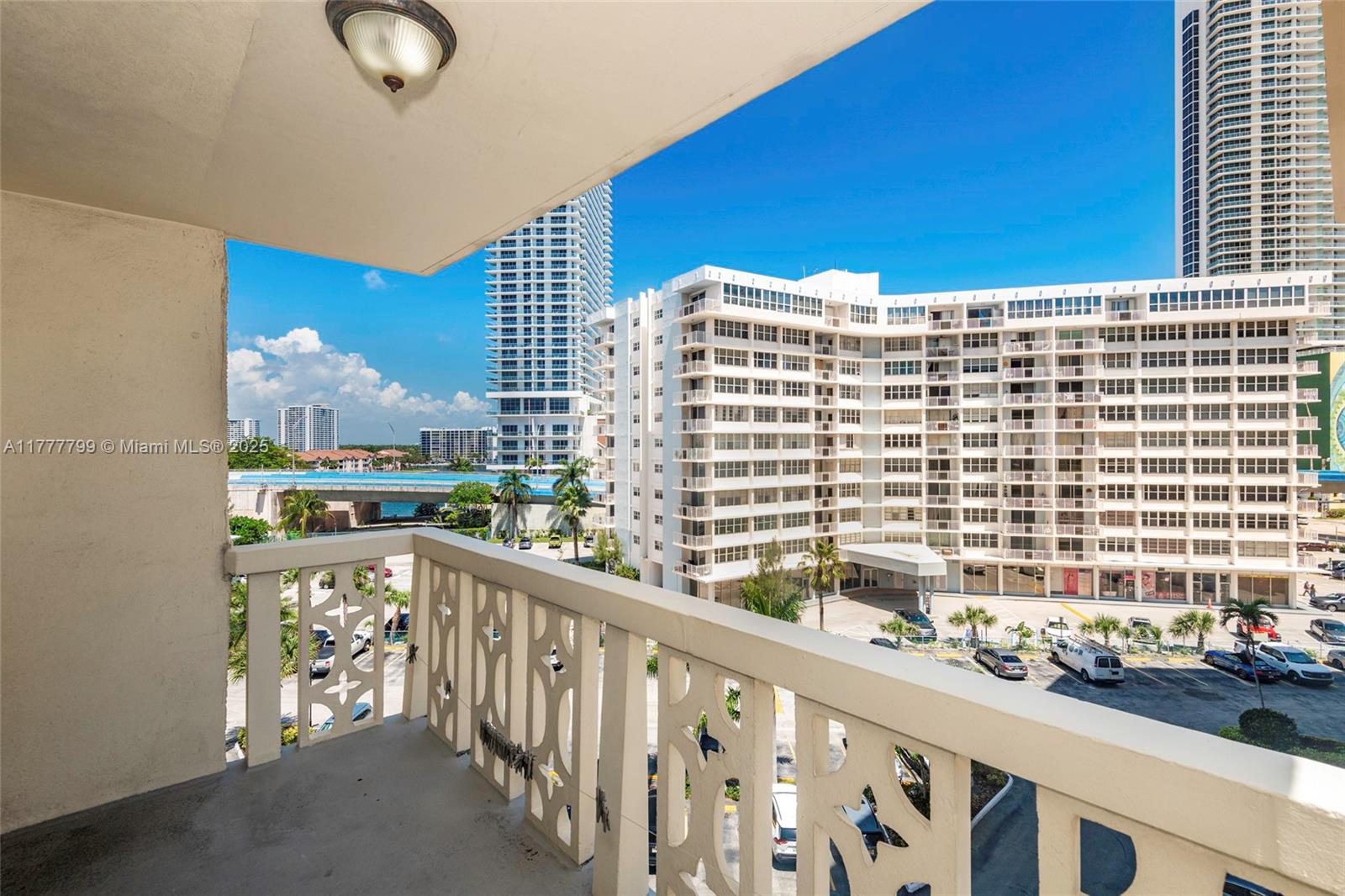 A balcony with a decorative white railing overlooks a parking lot and nearby high-rise buildings — 1817 S Ocean Dr # 628, Hallandale Beach FL 33009, HALLANDALE BEACH, FL